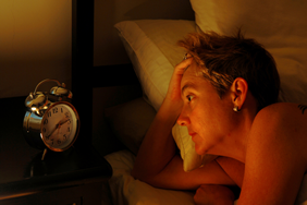 woman staring at clock in bed